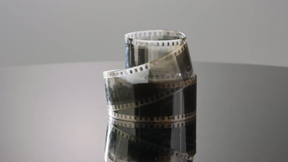 35mm film negative rotating on a reflective surface. Studio shot alt