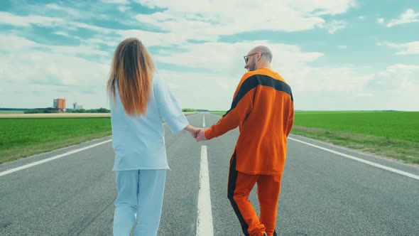 A Couple of Lovers Leisurely Stroll Along the Road on a Sunny day.The Guy Is Holding His the Girl's alt