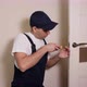 Portrait of Young Locksmith Workman in Blue Uniform Installing Door Knob - VideoHive Item for Sale