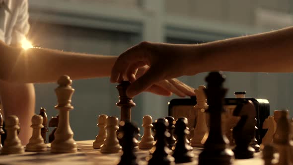 People play chess in a dark room with warm lighting. Close-up