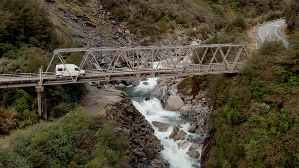 Camper Van Crossing a Narrow Bridge Over a Mountain River in New Zealand (Aerial Drone Shot) alt