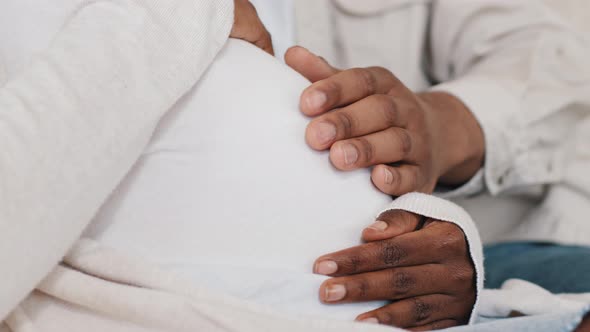 Closeup Male and Female Hands Stroking Pregnant Belly of Woman in White Clothes African American alt