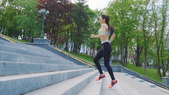 Fit Woman Jogging on Staircase in Park alt