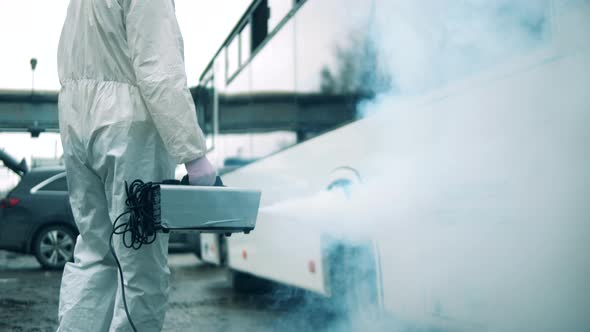 Specialist Is Spraying Disinfectant To Sanitize the Bus alt