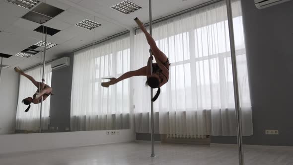 Flexible Woman Dancing on Pole in Studio