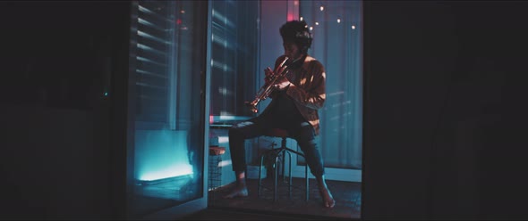 Bare feet trumpeter playing in his apartment with red and blue neon light alt