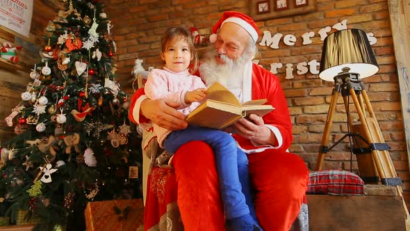 Santa Claus Sitting in Chair and Holding Little Girl 