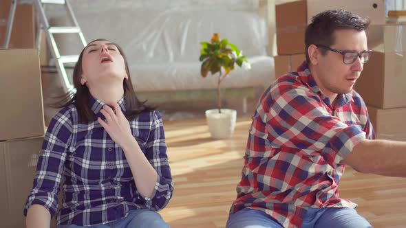 Tired Young Couple with Laptop on the Background of Boxes for Moving New Home alt