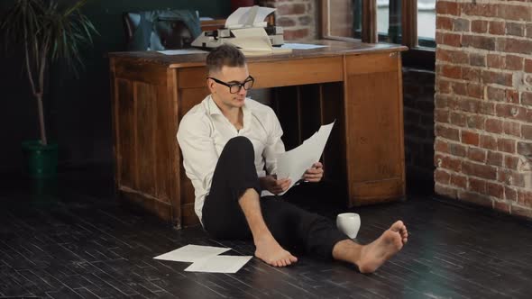 Man Reads Pages on Floor alt