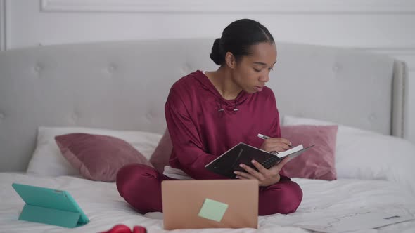 Front View Wide Shot of Young Engrossed Concentrated Woman Writing in Sketchbook Checking Email on alt