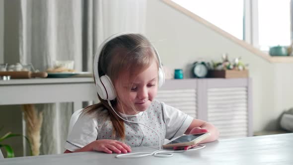 Little Girl in Headphones Enjoying Music on Smartphone