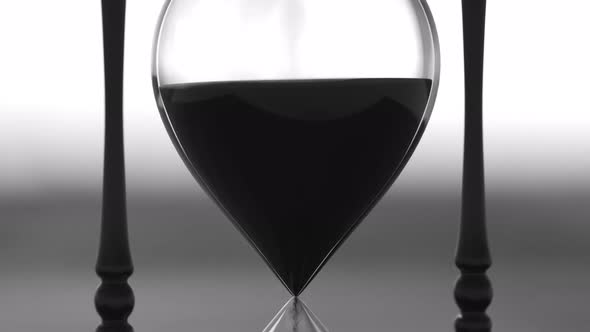 Sand running through the bulbs of retro hourglass on the head of depressed man. alt