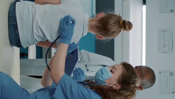 Vertical Video Woman Nurse Using Stethoscope on Small Kid to Do Pulse Exam alt