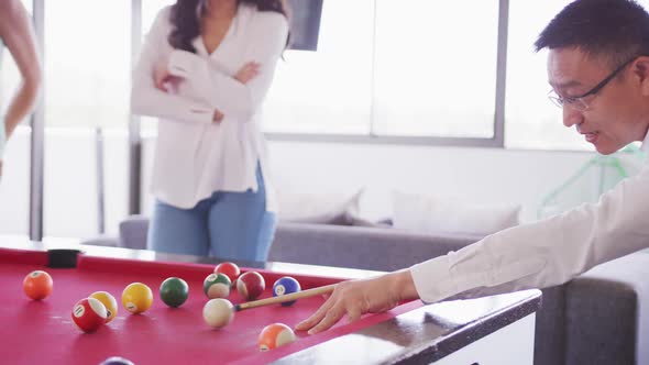 Senior businessman playing billiards in modern office in slow motion alt