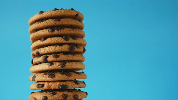 A stack chocolate chip cookies rotate on a blue background.American cookies close up alt