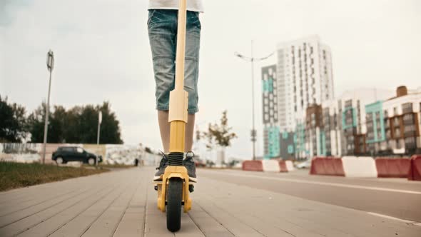 Boy Rides An Electric Scooter Around The City On in Summer Feet Close Up alt