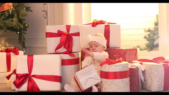 A Little Girl Child is Sitting Among the Gifts Looking at