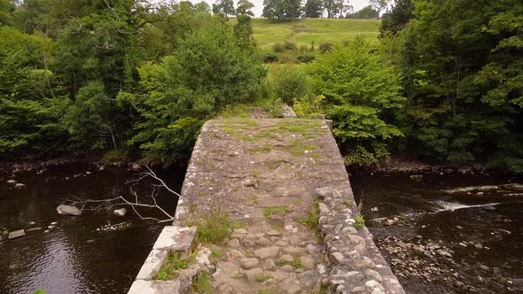 aerial view of cobbled pathway over cromwells bridge over rolling stream alt