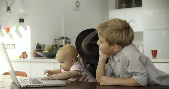 Father and children with laptop in kitchen