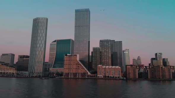 Low slider shot of Canary Wharf buildings along the Thames at sunset alt
