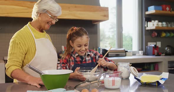 Grandmother watching the girl happily while mixing flour 4K 4k alt