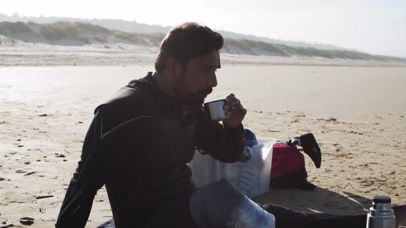 Side View of Man with Disability Drinking Tea After Surf Workout alt