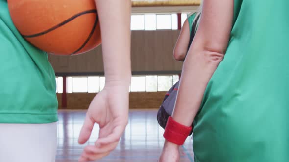 Diverse female basketball team practice dribbling ball, wearing face masks alt
