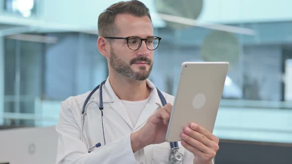 Middle Aged Male Doctor Browsing Internet on Tablet alt