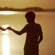 Silhouette of a boy with homemade origami ship in the evening. - VideoHive Item for Sale