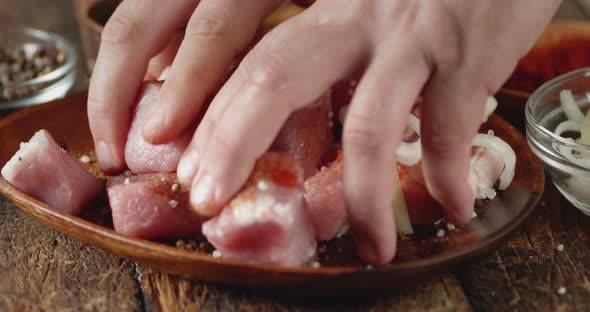 Men's Hands Stir Raw Pork Kebab with Spices and Onions.  alt
