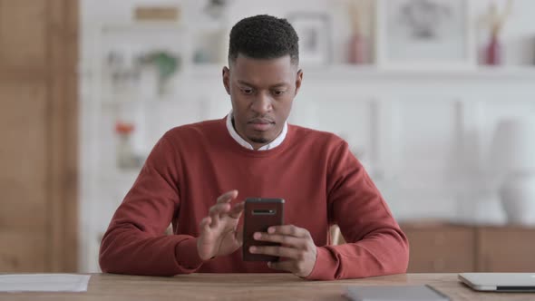 Attractive African Man using Smartphone in Office alt