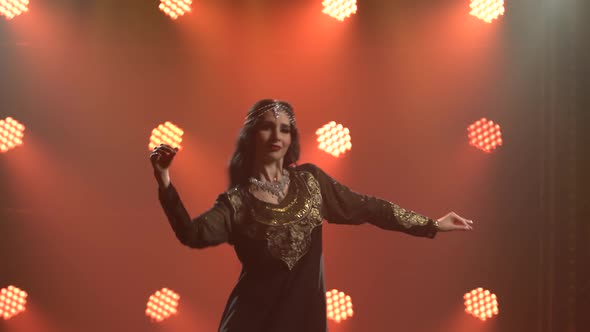 Beautiful Belly Dancer Woman Graceful Dancing in a Black Oriental Dress. Shot in a Dark Studio with alt