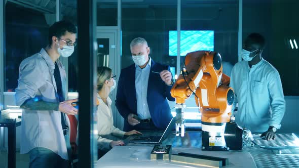 Team of IT Engineers in Face Masks are Discussing Robots alt