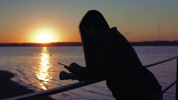 Woman Walking on Pier Using Mobile Phone Black Woman Silhouette on Sunset