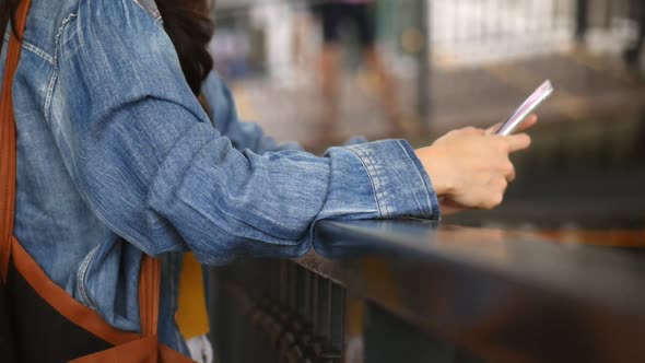 Closeup hand beautiful young Asian girl using smartphone texting messenger at outdoors.