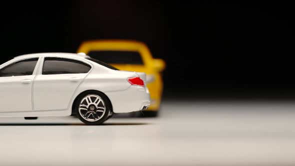 Yellow toy car bumps into standed white toy car