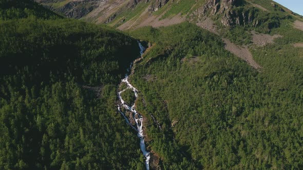River with waterfalls in alpine landscape of Northern Norway, aerial dolly out alt