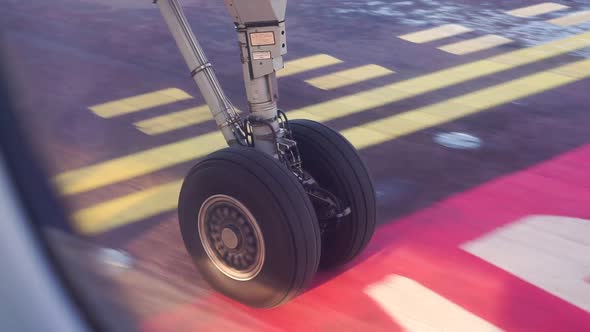 Airplane landing gear taxiing on airport runway on sunrise alt