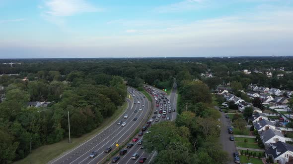 An aerial view next to a busy parkway in the evening, during rush hour. The camera dolly in along th alt