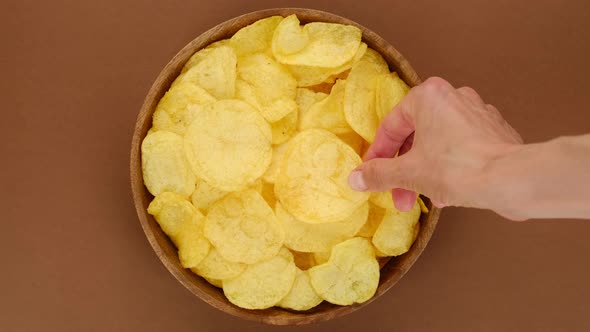 Potatoes chips. Hands of different people that take chips from bowl alt