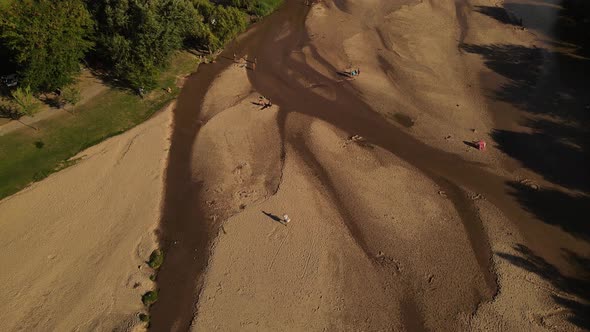 4K Hawker peddler walking by river shore selling ice cream. Aerial top down view. Cordoba in Argenti alt