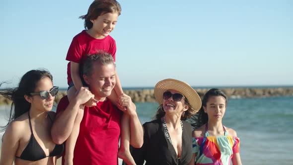Medium Shot of Happy Caucasian Family Walking Along Sea Shore alt