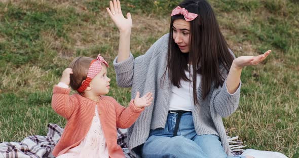 Mother and a Small Daughter, Spends Time Together in a City Park on a Picnic. Young Woman and Little alt