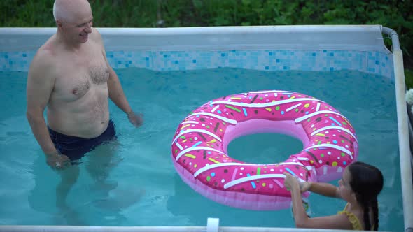 Grandfather and Granddaughter Swimming in the Pool