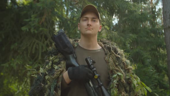 Portrait of Young Soldier in Ghillie Suit with Sniper Rifle Outdoors alt