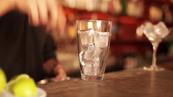 Bartender preparing cocktail by first squeezing fresh lime over ice alt