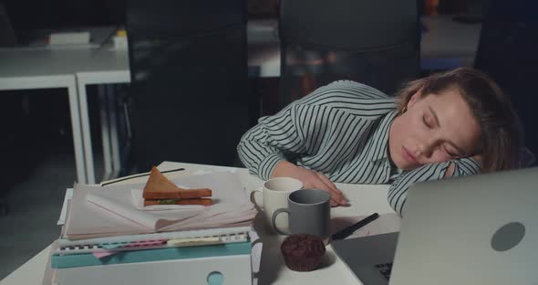 Sleepy Young Woman Office Worker Lying on Mess Table with Opened Notebook in Front of Her. Tired alt