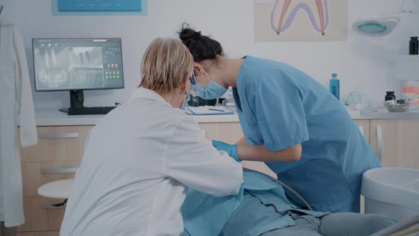 Stomatologist and Nurse Doing Extraction Procedure on Patient alt