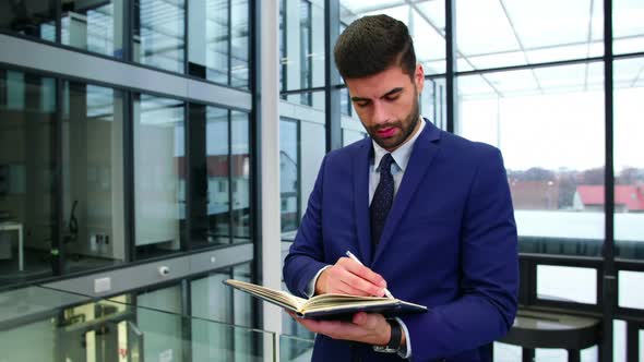 Businessman writing in diary at office alt