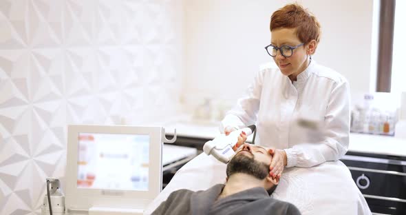 Beautician Making Ultrasound Face Lifting Procedure to a Man alt